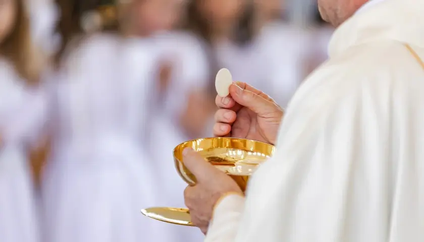Ksiądz trzymający hostię i kielich podczas komunii świętej.