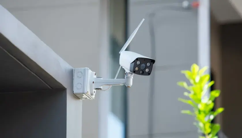 Caméra de surveillance blanche fixée sur un mur extérieur. Une question se pose : peut-on mettre une caméra de surveillance chez soi ?
