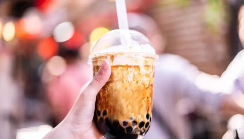 Ręka trzyma kubek z brązowym bubble tea. Czy bubble tea jest zdrowe? Zależy od składników, ale ten wygląda pysznie!