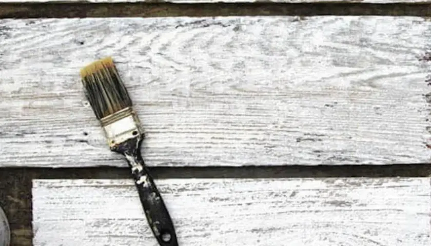 Pennello sporco su assi di legno bianco, pronto per la cementite per legno già verniciato.