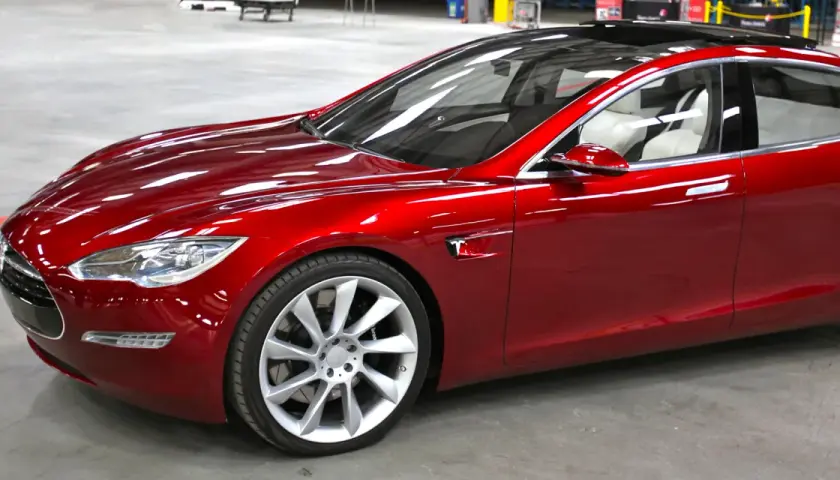 Czerwony Tesla, który mąż nie chce dać mi samochodu, lśni w słońcu.