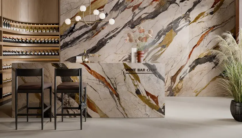 Elegante wine bar con scaffali in legno pieni di bottiglie, bancone in marmo con venature colorate e sedie in legno scuro. Il pavimento marmo e legno crea un ambiente raffinato.