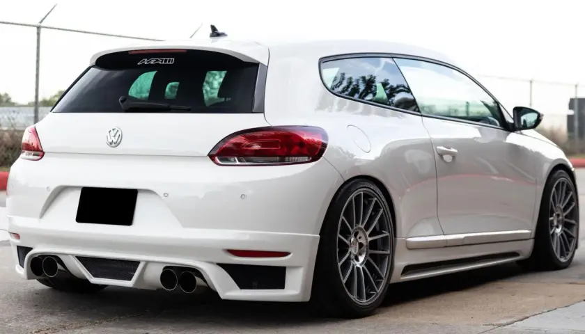 La parte posteriore di una Volkswagen Scirocco bianca, con un diffusore sportivo e quattro scarichi.