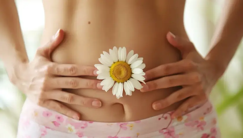 Delikatny brzuch z kwiatem rumianku, symbolizującym naturalne sposoby na biegunke.
