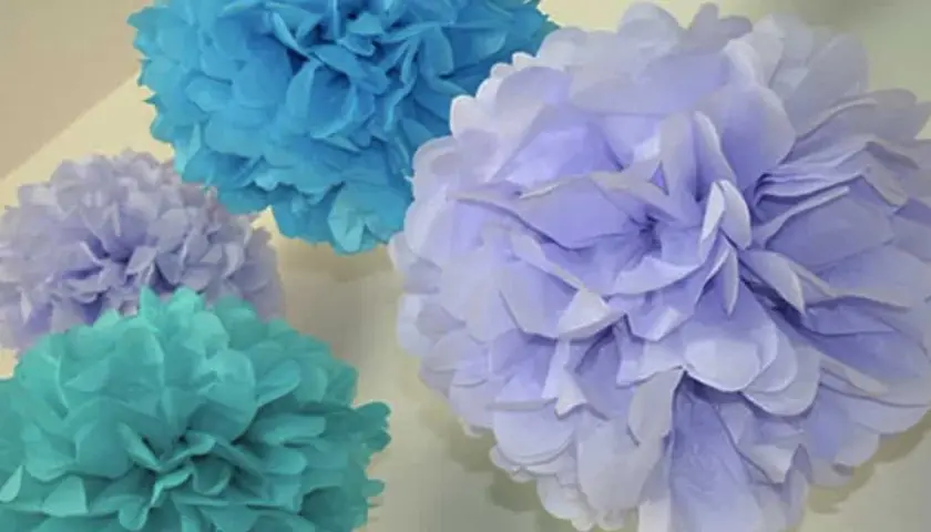 Pompones de papel pinocho en tonos azules y lilas, perfectos para manualidades decorativas.