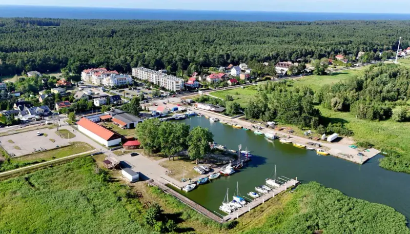 Widok na przystań jachtową i zabudowania w otoczeniu zieleni, idealne miejsce na camping Mierzeja Wiślana.