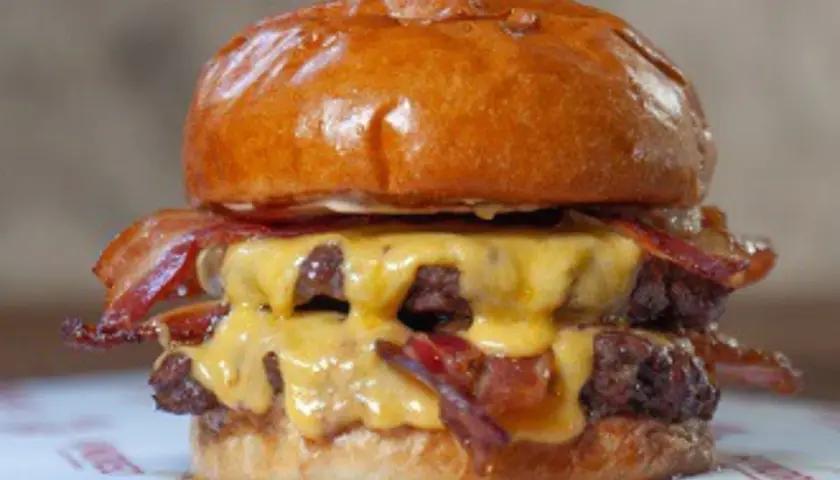 Jugosa hamburguesa doble con queso fundido y crujiente bacon, un festín que vale hundred Valencia.