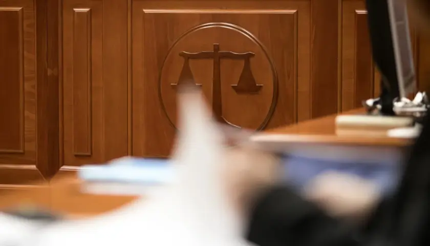 Drewniana ściana z symbolem wagi sprawiedliwości. Zastanawiasz się, ile trwa sprawa w sądzie cywilnym? Czas oczekiwania bywa różny.