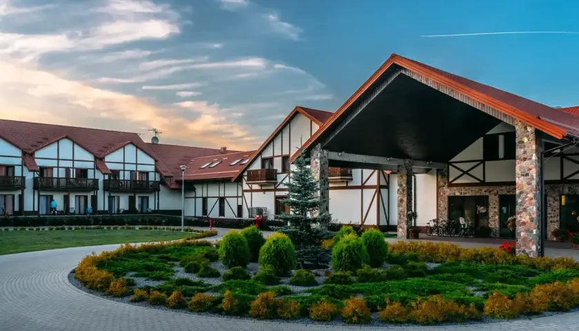 Hotel Mikołajki Leisure & Spa zaprasza do wypoczynku. Piękny budynek z kamiennymi elementami i zadbanym ogrodem.