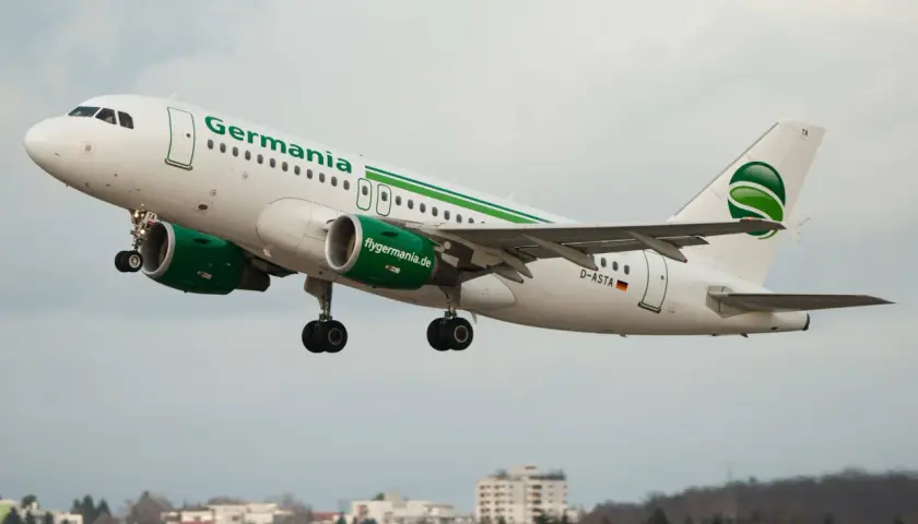 Samolot linii lotniczych Germania z zielonym logo startuje na tle pochmurnego nieba.