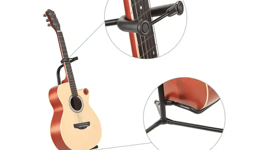 Akustyczna gitara oparta na stabilnym statywie na gitarę. Widoczne zbliżenia na mocowanie gryfu i podstawę.
