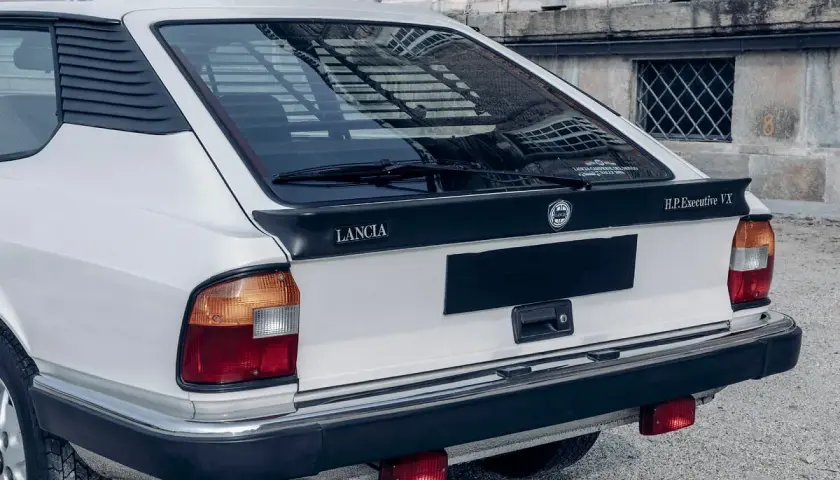 Tylna część białego Lancia Gamma Coupe z czarnym spoilerem i napisem "H.P.Executive VX".