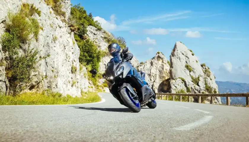 Motocyklista na sportowym motocyklu z power commanderem pokonuje zakręt na górskiej drodze, otoczony skalistymi zboczami i błękitnym niebem.