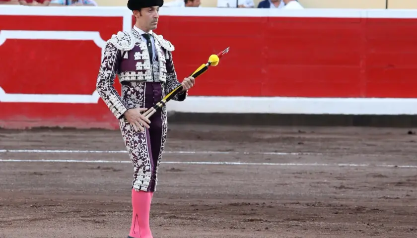 Torero español con traje de luces morado y blanco, listo para clavar banderillas.