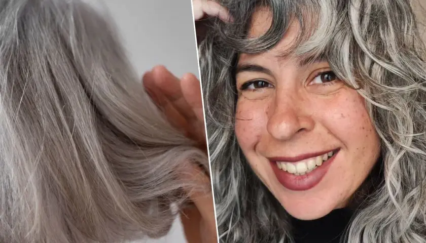 Una mujer sonríe mostrando su cabello con canas, que luce rizado y con mechones plateados.
