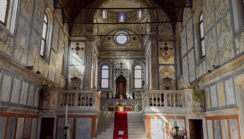 Intérieur de l'église Santa Maria dei Miracoli à Venise, avec son escalier rouge menant à l'autel, le tout orné de marbre.