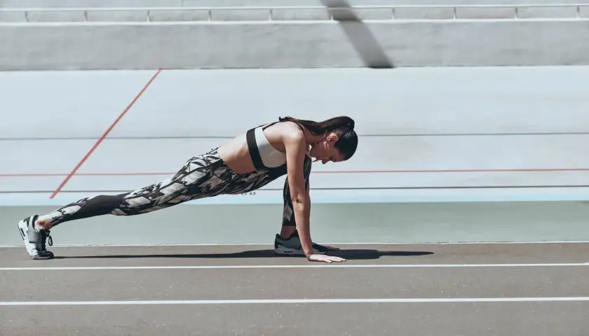 Kobieta wykonuje ćwiczenie typu stretching na bieżni.