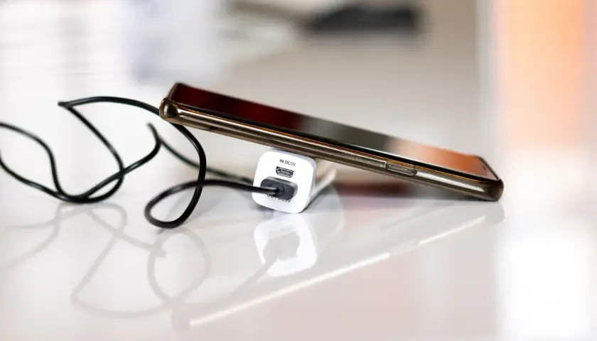 Smartfon podłączony do ładowarki, by zapobiec nadmiernemu zużyciu baterii.