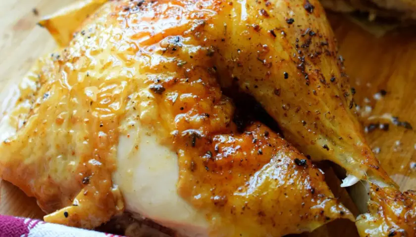 Un délicieux demi poulet BBQ, la peau dorée et brillante, prêt à être dégusté.