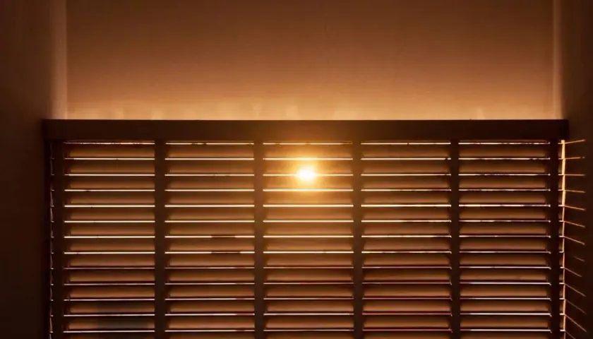 Luce solare filtrata da veneziane in legno, ideale per il calcolo risparmio energetico schermature solari.