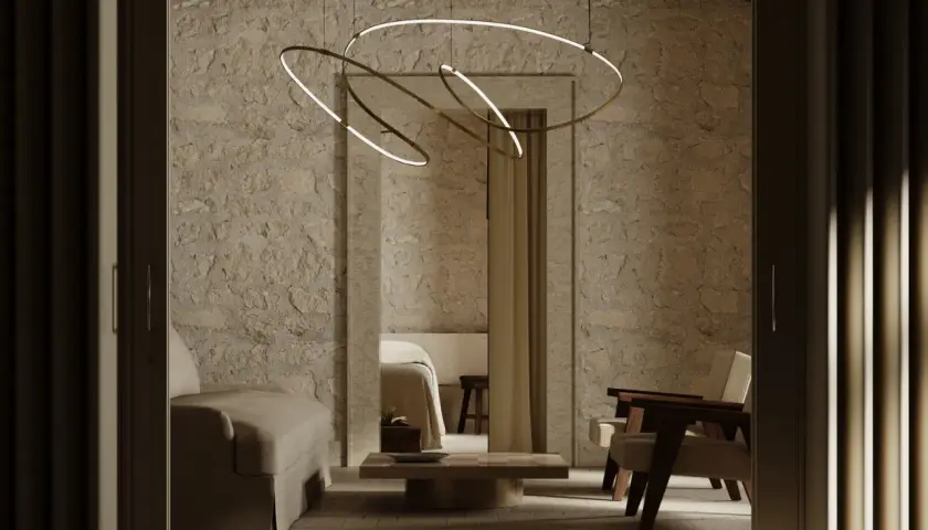 Nowoczesne lampy na poddasze skosy, wiszące nad kamiennym wnętrzem z sofą i fotelami.