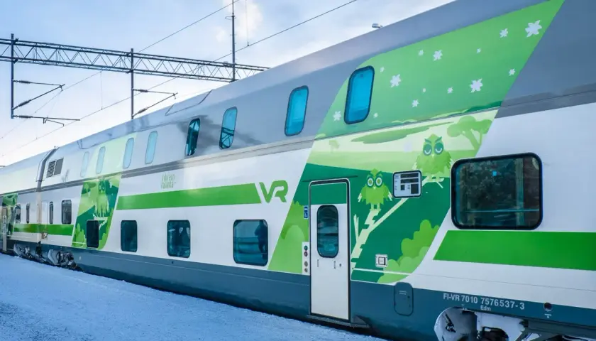 Ein moderner Doppelstockzug der VR in Finnland, verziert mit Eulen und Sternen, fährt durch eine verschneite Landschaft.