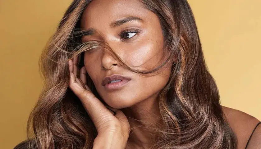Morena con cabello castaño y reflejos caramelo, un estilo que ilumina su rostro.