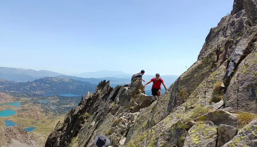 Trepando por rocas, un pic carlit con lagos turquesas de fondo.