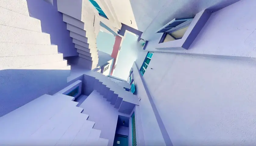 Escaleras y fachadas de color lavanda y blanco, con toques turquesa, que recuerdan a la muralla roja de Calpe.