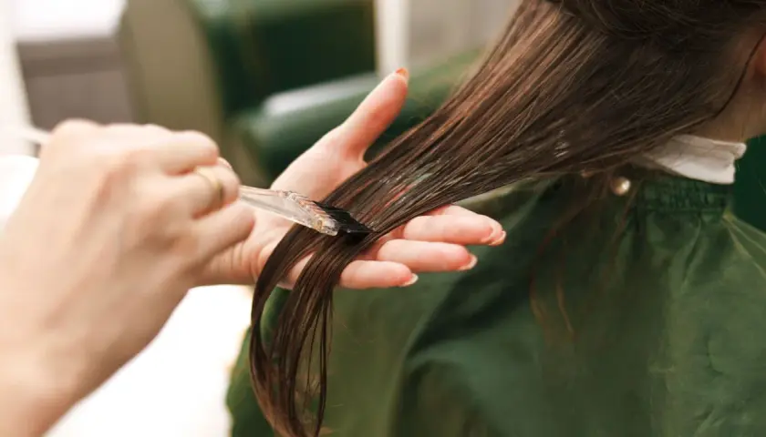 Manos aplicando tinte en el cabello. Cuidado con la alergia al tinte de pelo.