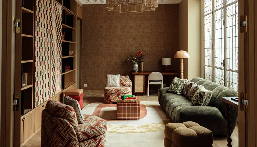 Salon cosy avec canapé vert, fauteuil à motifs, table basse cubique et étagères. L'ambiance invite à **acheter avant de vendre** ce style unique.