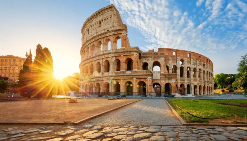 Il Colosseo all'alba, con i raggi del sole che illuminano l'anfiteatro. Vicino alla fermata metro Colosseo, linea B.