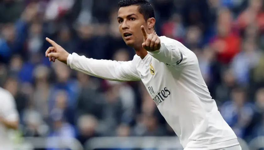 Cristiano Ronaldo w białej koszulce Realu Madryt, z uniesionymi palcami, jakby ogłaszał swój wzrost.