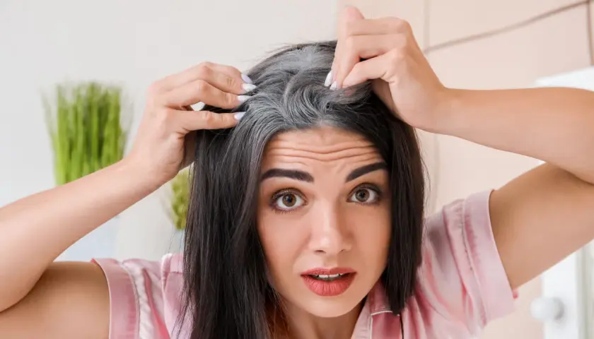 Mujer preocupada por sus canas, buscando una solución natural con mechas sin amoniaco.
