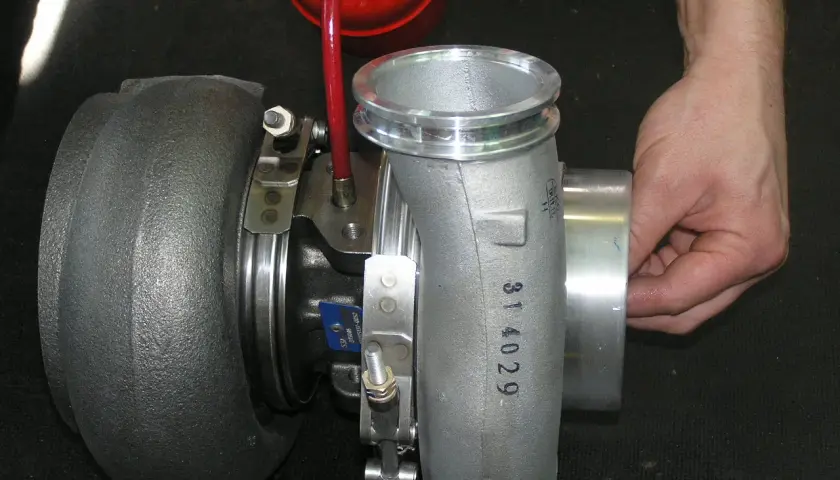 Ustawienie sztangi turbiny domowym sposobem. Dłoń trzyma element turbosprężarki, obok czerwony zbiorniczek.