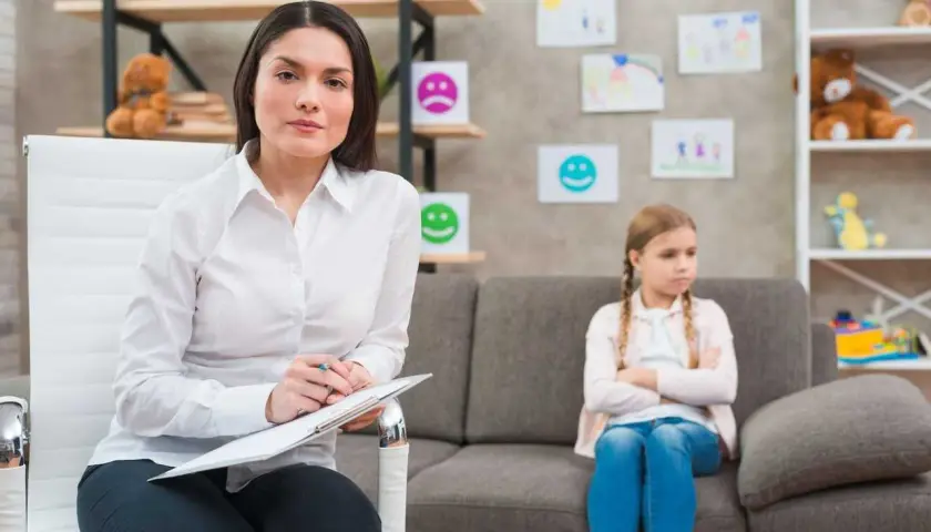 Psycholog z notatkami podczas sesji z dzieckiem. To przykład przygotowania pedagogicznego dla psychologów, wspierającego rozwój emocjonalny najmłodszych.