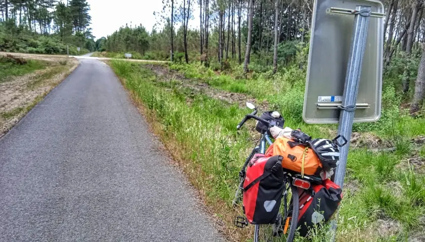 Bicicleta cargada lista para explorar las landas. El camino se abre paso entre pinos y vegetación exuberante.