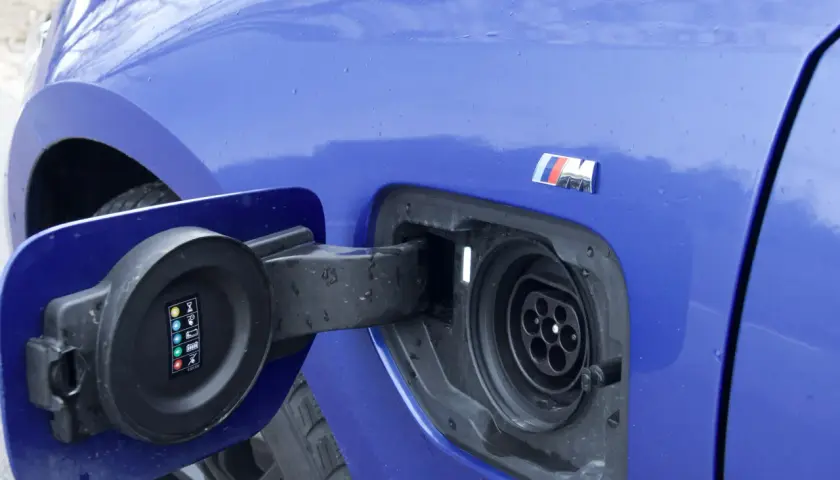 Niebieskie BMW 330e z otwartą klapką gniazda ładowania. Widoczny symbol M.