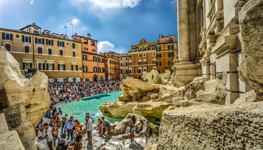 Fontana di Trevi, un vero gioiello tra gli imperdibili di Roma, affollata di turisti che ammirano la sua maestosità sotto un cielo azzurro.