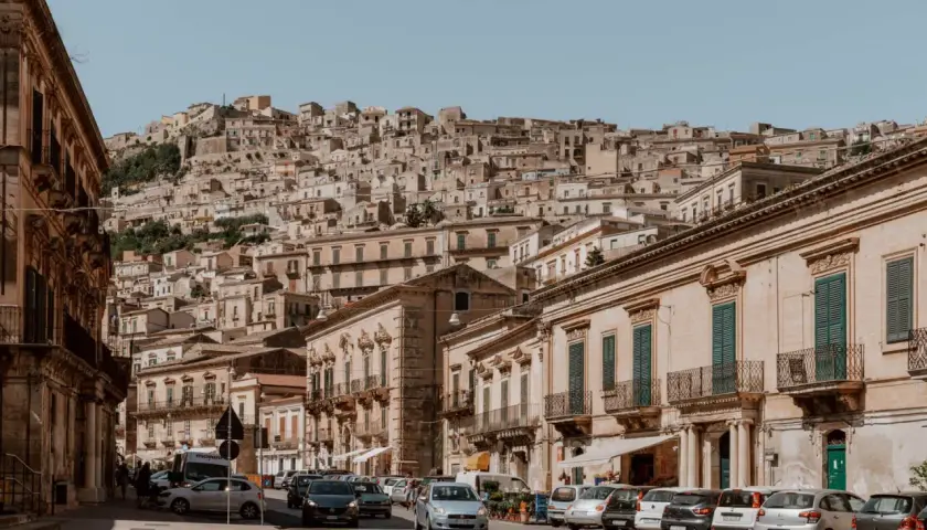 Cars navigate a steep, narrow street in a Sicilian town. Driving here might be challenging, but the views are worth it!