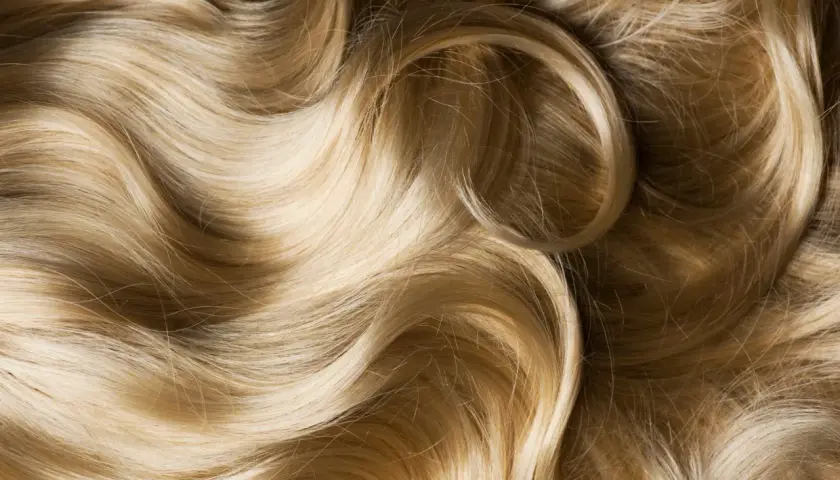 Ondas doradas y rubias de pelo sedoso, con reflejos de luz que resaltan su brillo y suavidad.