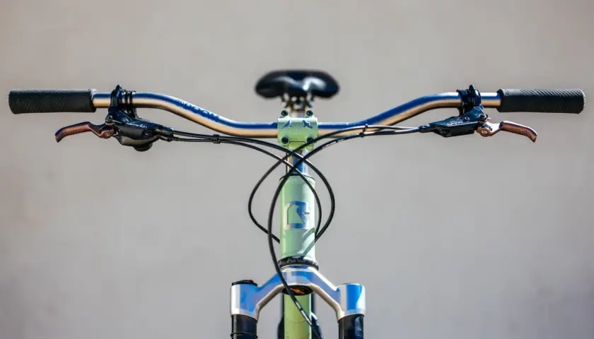 Close-up of a bicycle's handlebars and front fork, featuring Hayes Dominion A4 brakes, ready for a review.