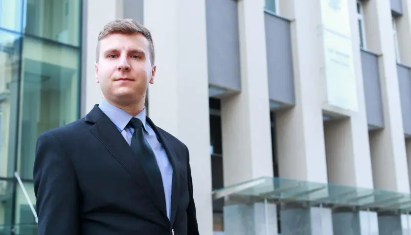 Mężczyzna w garniturze przed nowoczesnym budynkiem.
