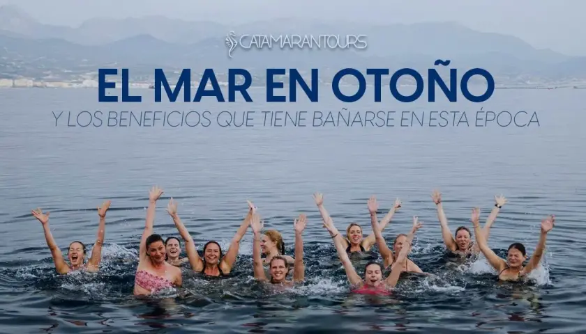 Grupo de personas nadando en el mar con los brazos en alto, disfrutando de los beneficios de bañarse en otoño.