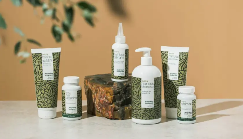 En samling hårvårdsprodukter med biotin, inklusive schampo, balsam, serum och kosttillskott för starkare hår.
