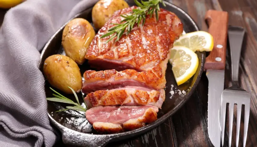 Un délicieux magret de canard au barbecue, servi avec des pommes de terre rôties, du romarin et des quartiers de citron.