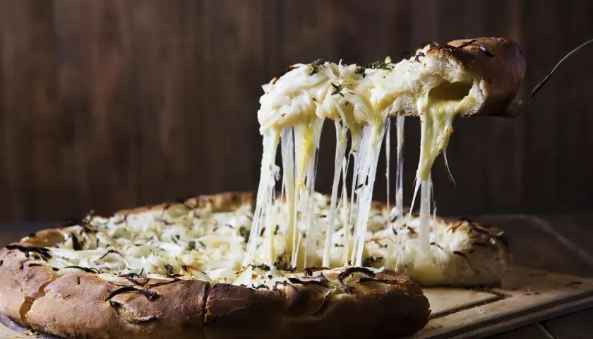 Rozpływający się ser ciągnie się z kawałka pizzy quattro formaggi, tworząc apetyczny widok.