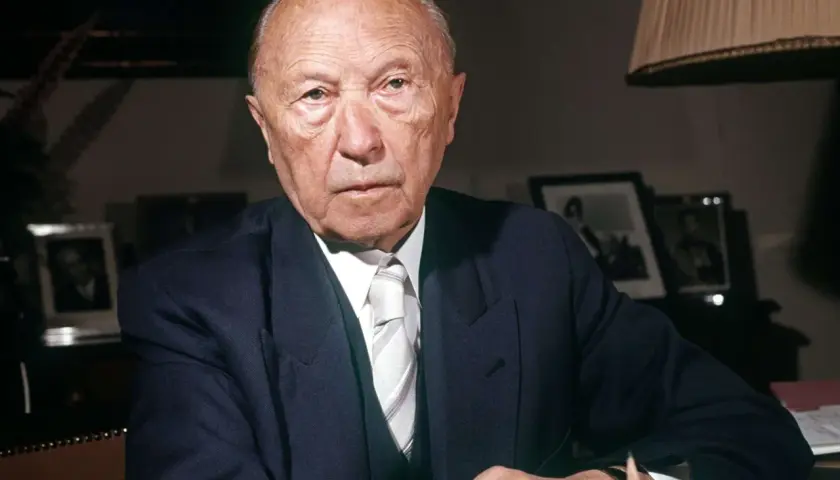 Konrad Adenauer, der von 1949 bis 1963 Bundeskanzler der Bundesrepublik Deutschland war, sitzt im Anzug am Schreibtisch.