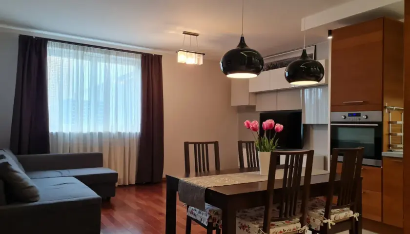 Nowoczesny salon z jadalnią, kanapą, stołem i kwiatami.