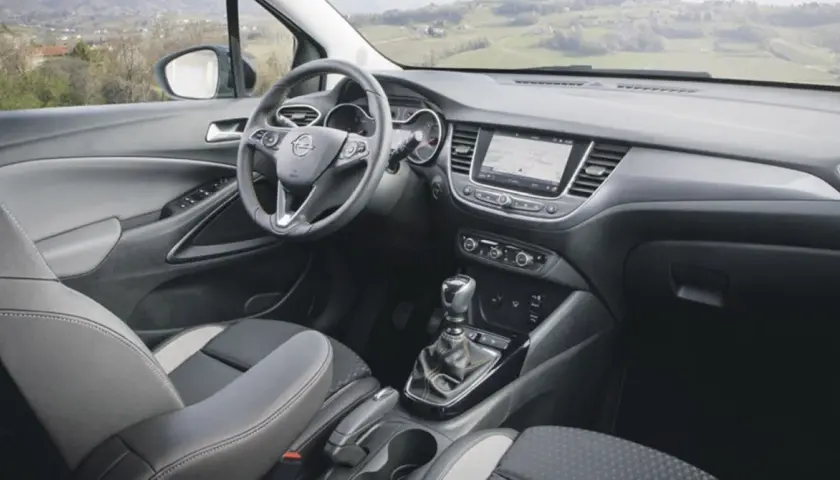 Interior del Opel Crossland X con asientos grises y negros, volante multifunción y pantalla táctil.